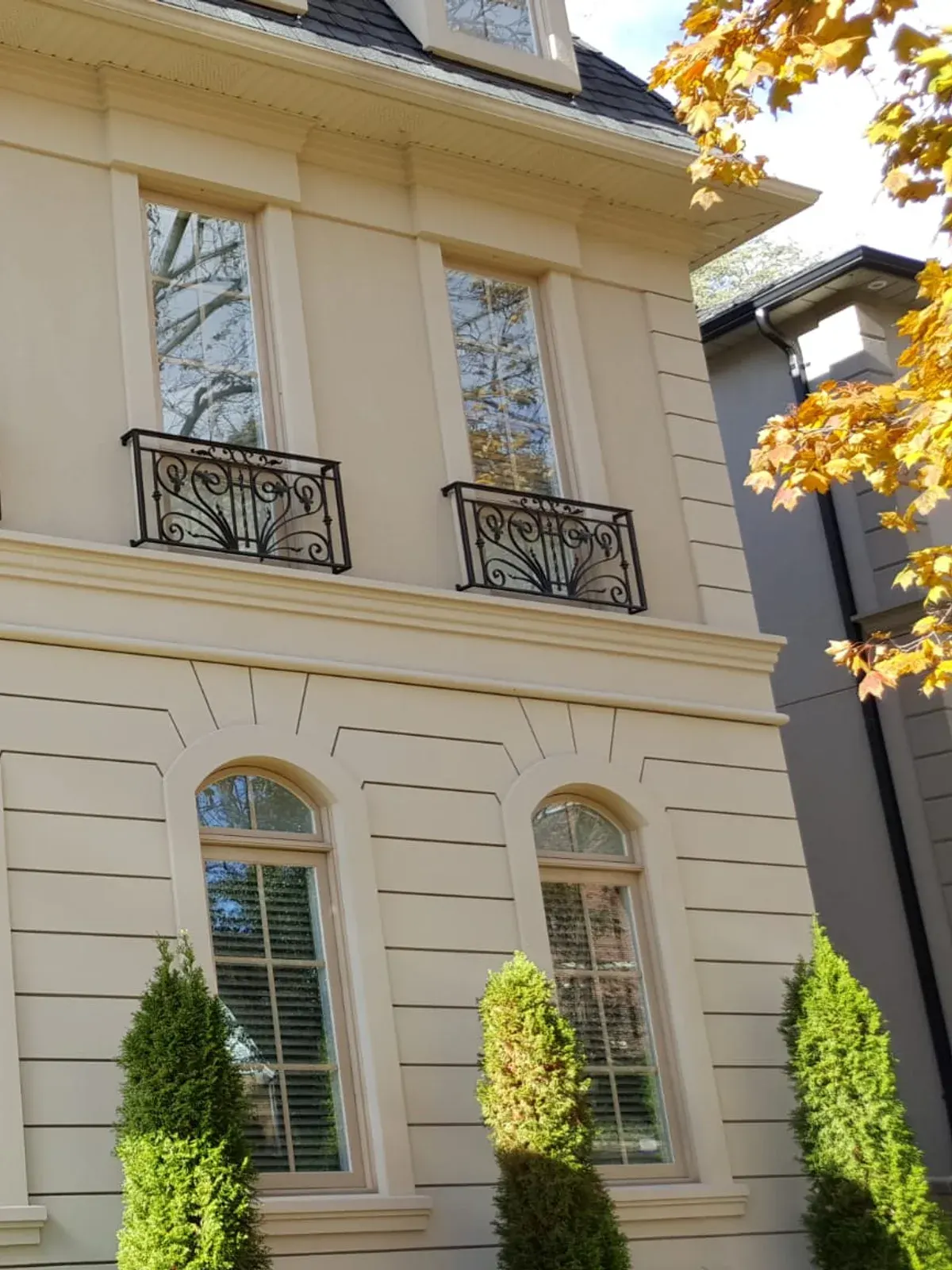 Upper facade with wrought-iron balconies, arched windows and smooth stucco
