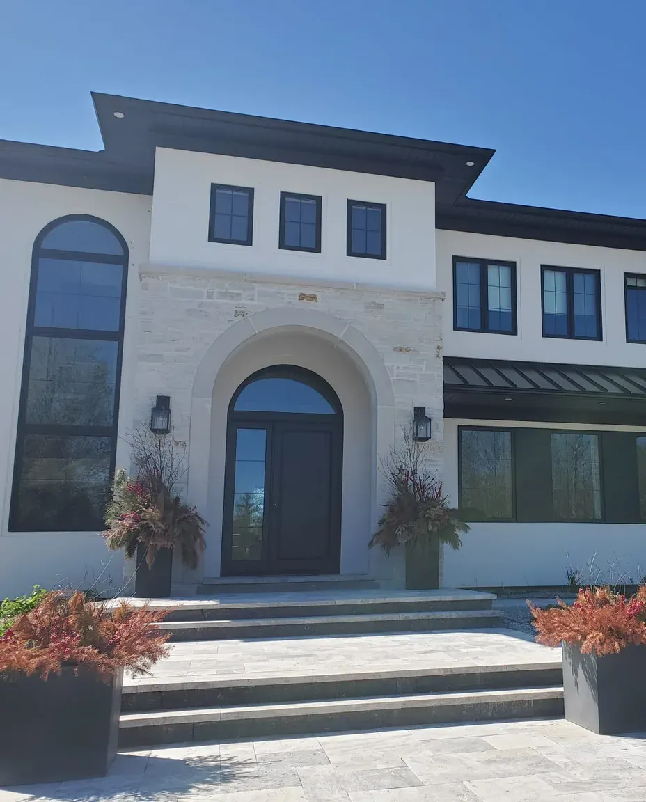 Custom residence finished by ITALSTUCCO — smooth stucco and limestone facade with an arched entrance