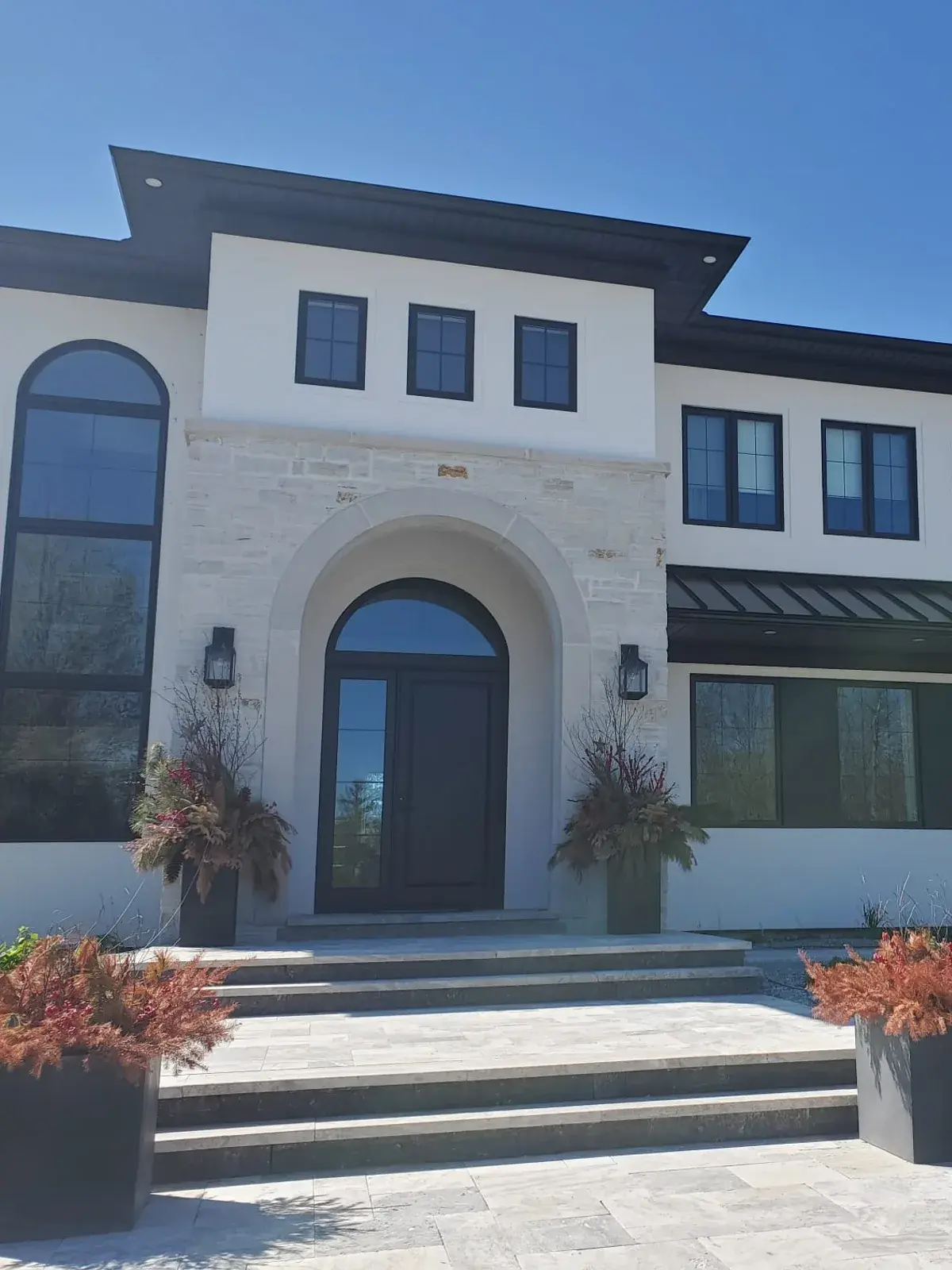 Modern custom residence with a smooth stucco arched entrance and limestone facade